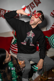 Weihnachtlicher Hoodie Mockup – Mann feiert mit Freunden, festliche Stimmung mit Deko und Licht.

